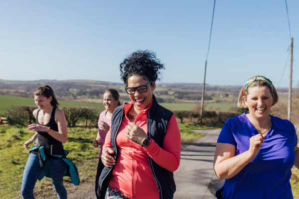 A group of mid adult women jogging outside and smiling